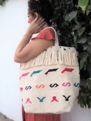 Bolso realizado en kilim, decorado en flecos de algodón, monedas y caracolas
