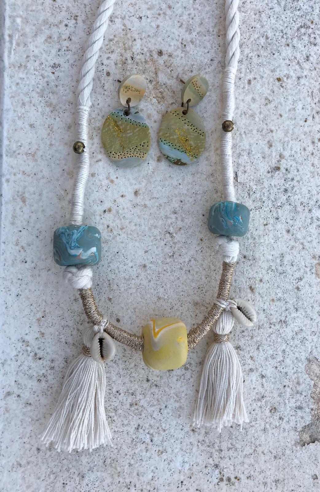 collar de cerámica en tonos azules y amarillos con borlones y pendientes en tonos tostados y azules