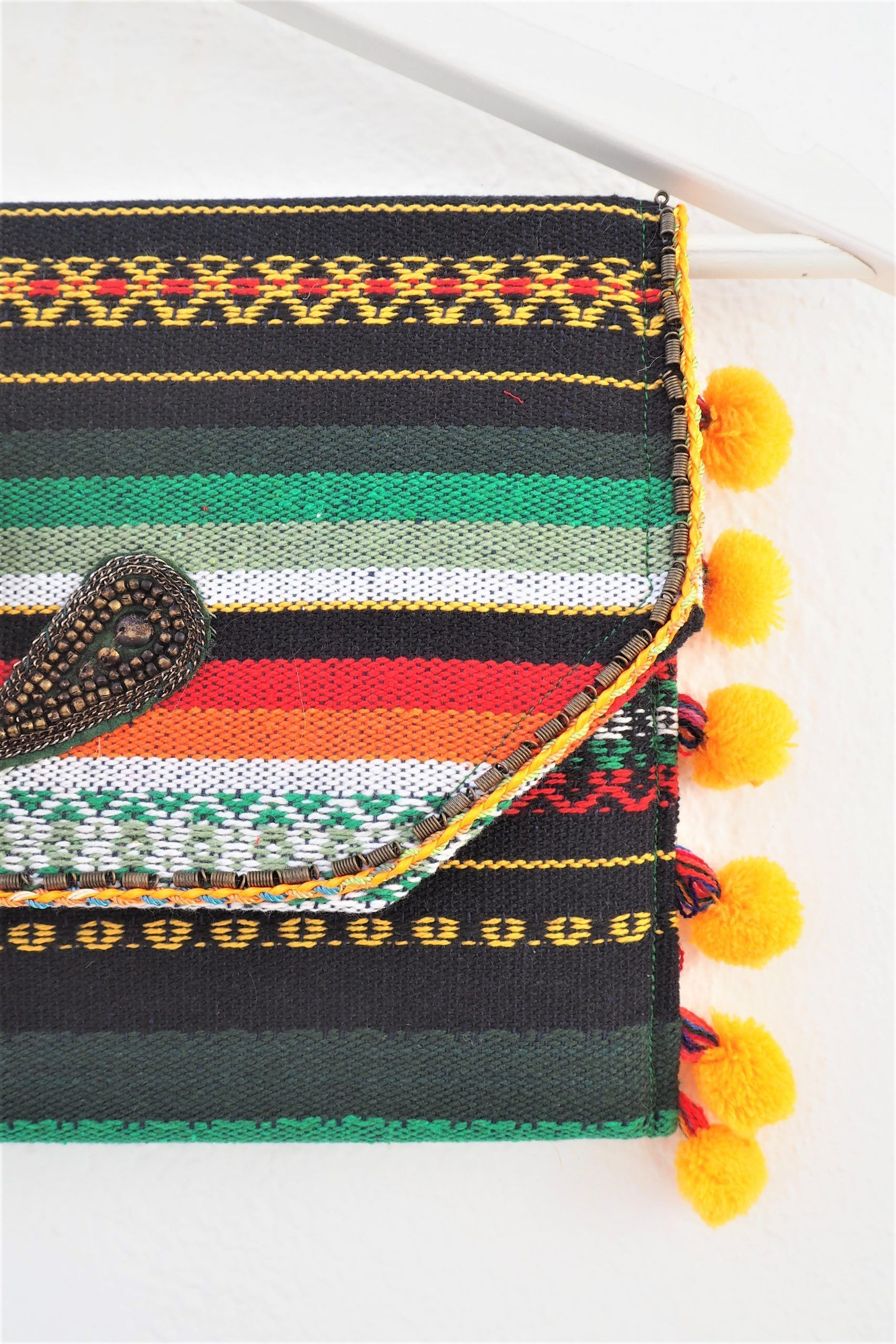 cartera de mano de estilo étnico de colores vivos y borlones y abalorios
