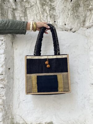 Bolso de estilo bohemio, en tonos negro y ocre, decorado con originales borlones.