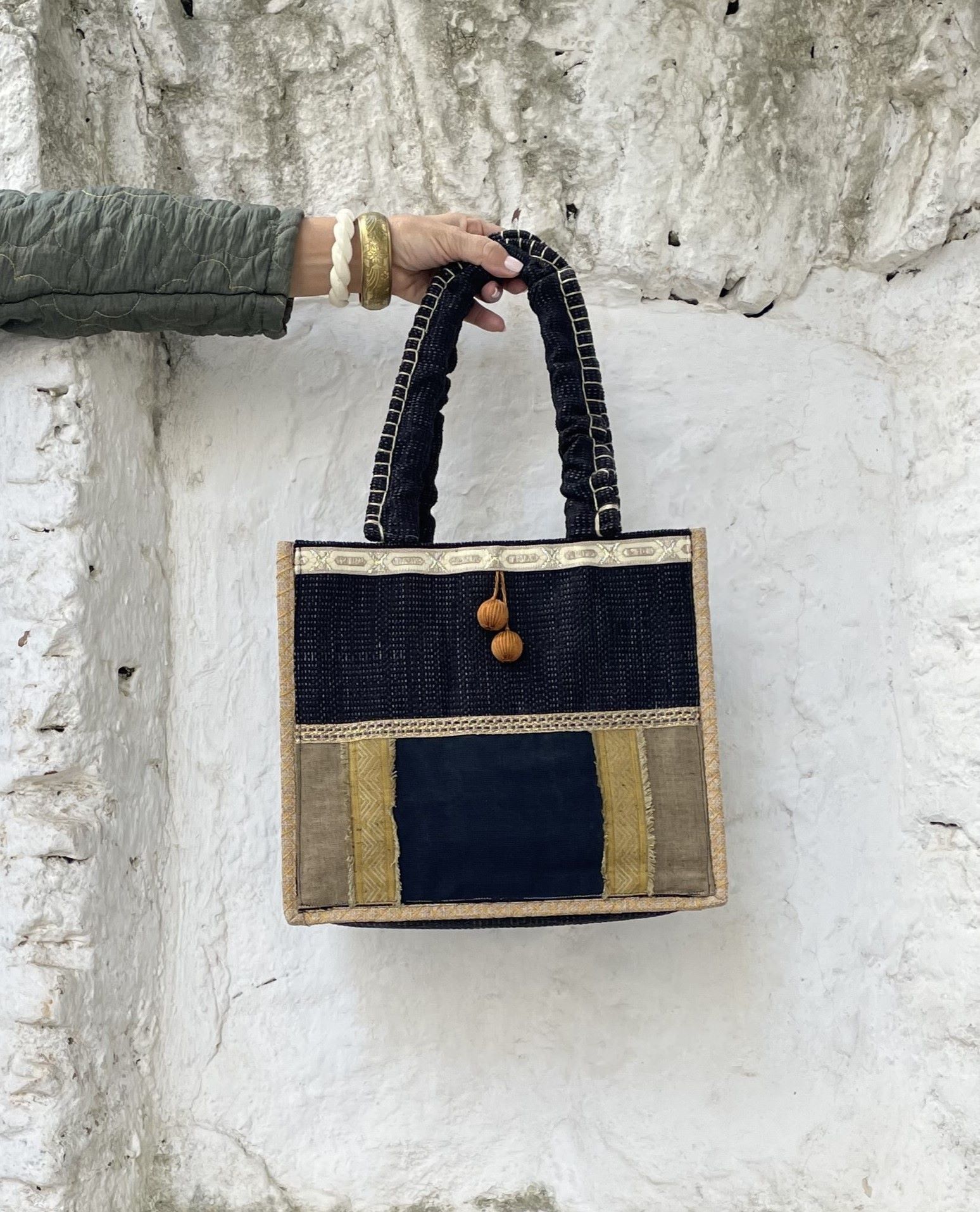 Bolso de estilo bohemio, en tonos negro y ocre, decorado con originales borlones.