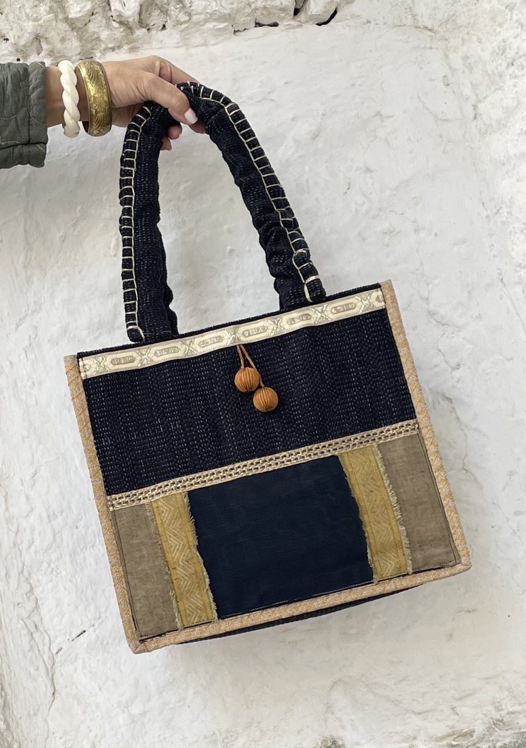 bolso negro y ocre, realizado en unos preciosos tejidos, decorado con borlones